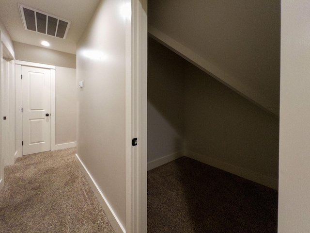 hall featuring baseboards, visible vents, and dark colored carpet