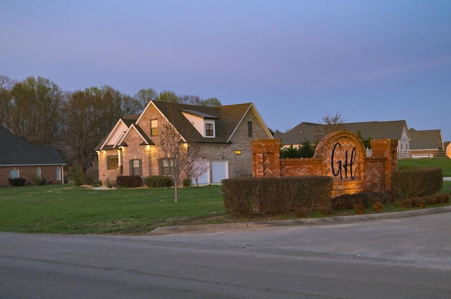 view of front of house featuring brick siding, a garage, and a front lawn