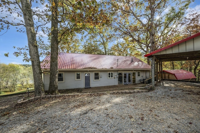 back of house featuring metal roof, french doors, and driveway
