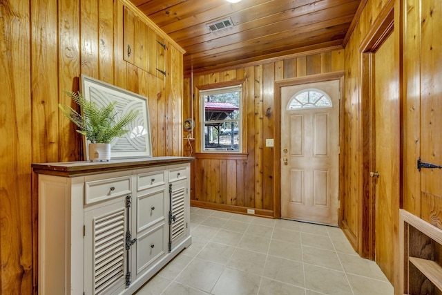 entrance foyer featuring wood ceiling, visible vents, light tile patterned floors, and wood walls
