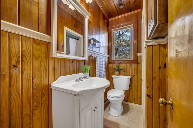 bathroom featuring visible vents, wooden walls, toilet, tile patterned floors, and vanity