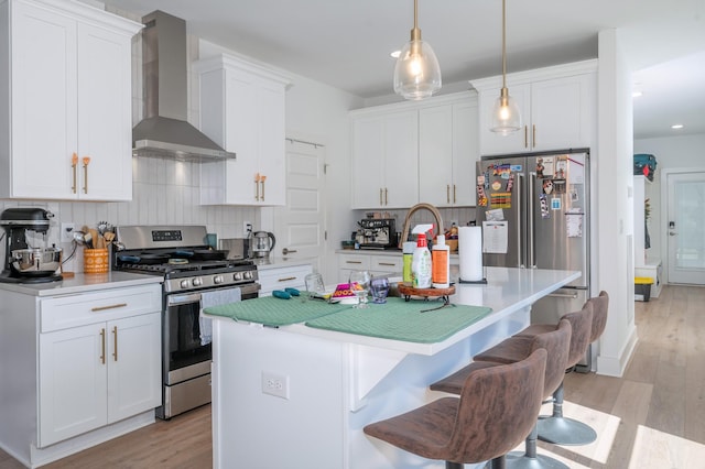kitchen featuring wall chimney range hood, light wood finished floors, tasteful backsplash, and gas stove