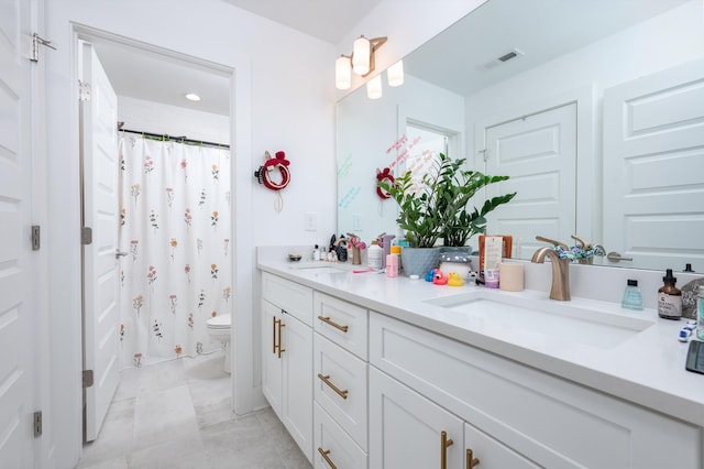 bathroom with a shower with curtain, toilet, a sink, and double vanity