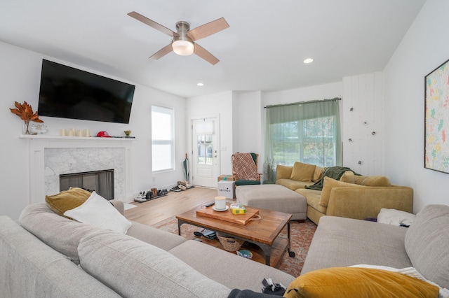 living area with a ceiling fan, a healthy amount of sunlight, a fireplace, and wood finished floors