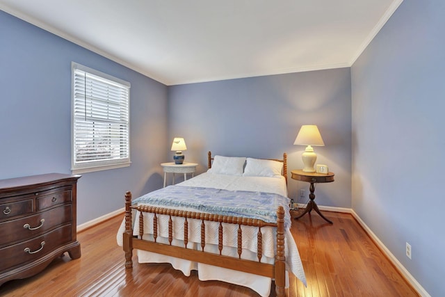 bedroom with baseboards, wood finished floors, and crown molding