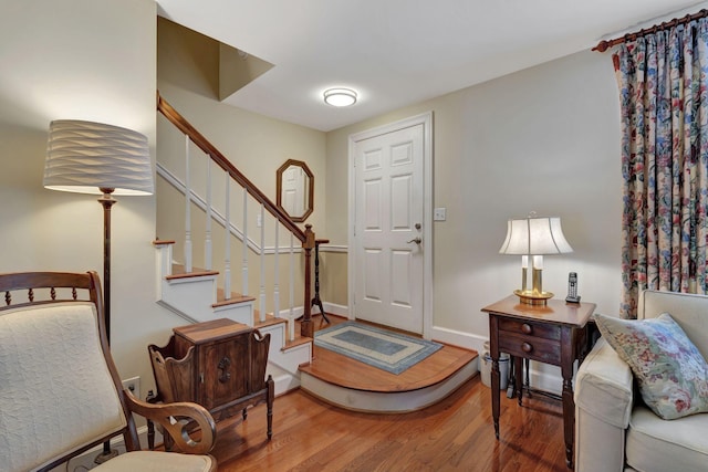 foyer entrance with baseboards, stairs, and wood finished floors