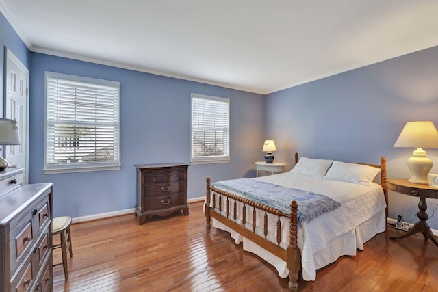 bedroom with multiple windows, ornamental molding, baseboards, and hardwood / wood-style floors
