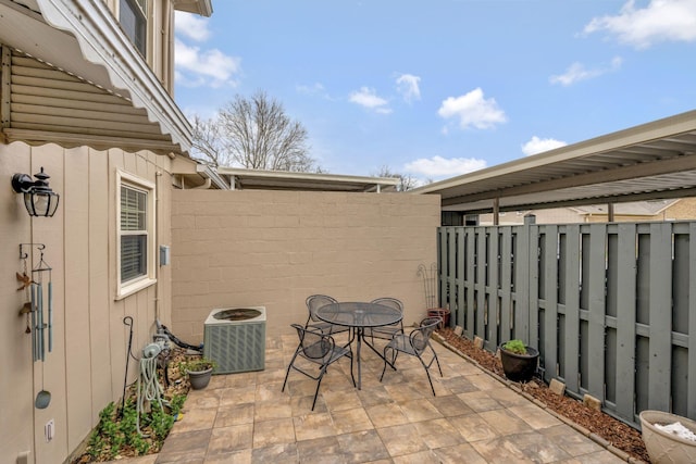 view of patio with cooling unit, outdoor dining area, and fence