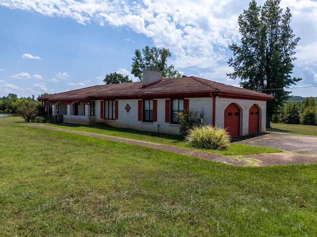 2589 Presley Ridge Rd, Sardis, TN 38371 - view of front of house featuring a tile roof, aphalt driveway, a front lawn, brick siding, and a garage