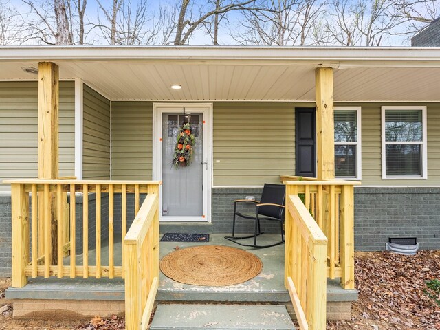 property entrance featuring brick siding and a porch
