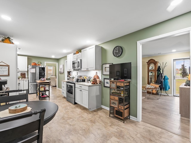 kitchen with white cabinetry, stainless steel appliances, baseboards, and tasteful backsplash