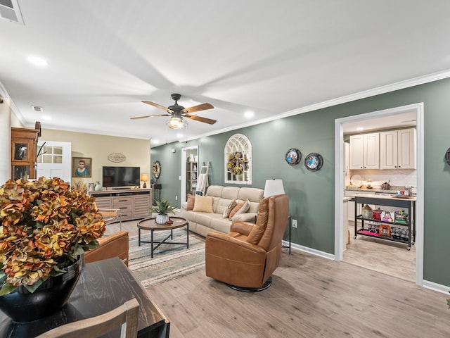 living room with visible vents, baseboards, ornamental molding, a ceiling fan, and light wood-style floors