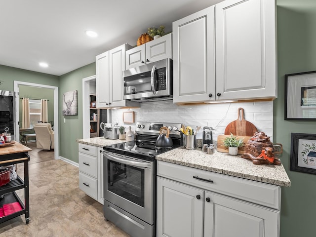 kitchen featuring decorative backsplash, white cabinets, stainless steel appliances, and recessed lighting