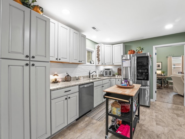 kitchen featuring visible vents, stainless steel appliances, tasteful backsplash, white cabinetry, and a sink