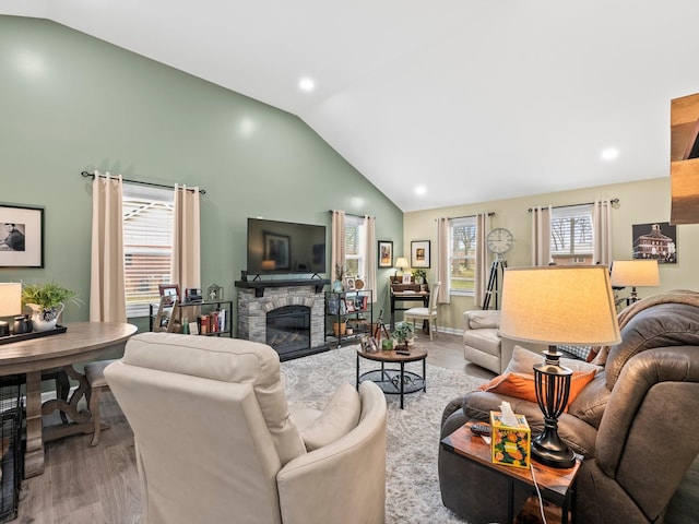 living area featuring a fireplace, baseboards, vaulted ceiling, and wood finished floors