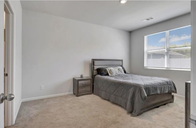 bedroom featuring visible vents, light colored carpet, and baseboards