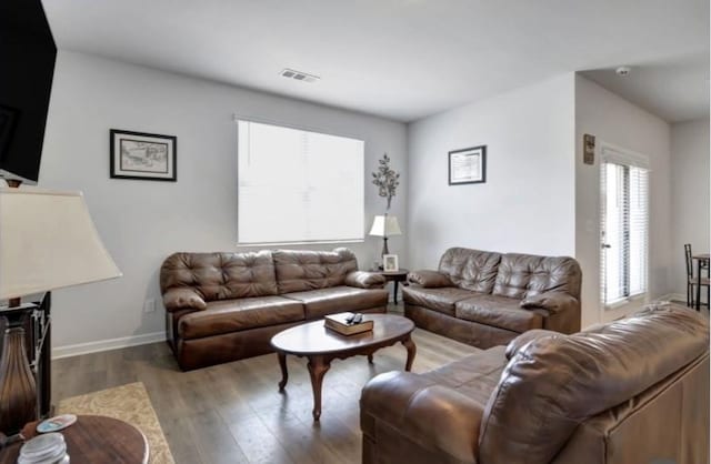 living area with visible vents, wood finished floors, and baseboards