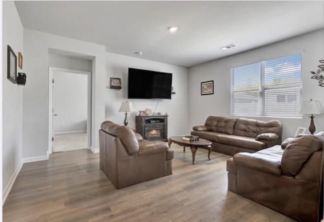 living area with baseboards, light wood-type flooring, and visible vents