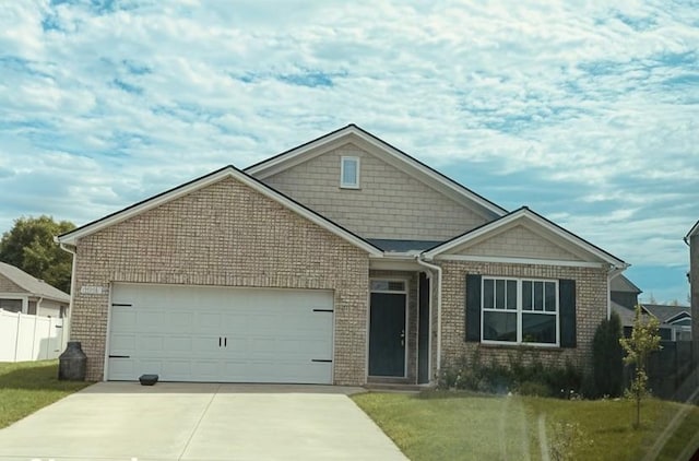 craftsman-style home with a front lawn, brick siding, concrete driveway, an attached garage, and fence
