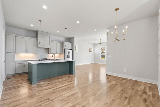 kitchen with an inviting chandelier, light countertops, stainless steel refrigerator with ice dispenser, and light wood-style floors