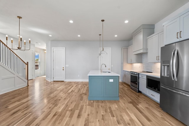 kitchen with decorative backsplash, light countertops, appliances with stainless steel finishes, a sink, and light wood-type flooring
