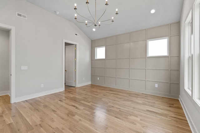 spare room featuring lofted ceiling, visible vents, a chandelier, and light wood finished floors