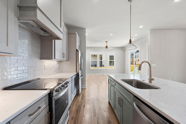 kitchen with decorative backsplash, custom exhaust hood, appliances with stainless steel finishes, a sink, and gray cabinets