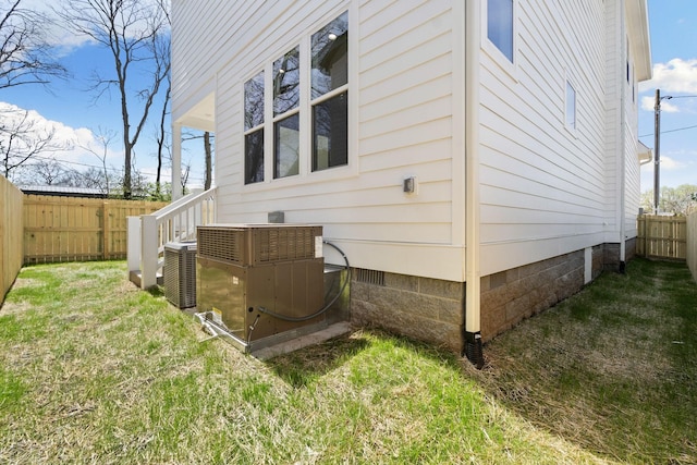 view of home's exterior featuring a lawn, central air condition unit, a fenced backyard, and crawl space