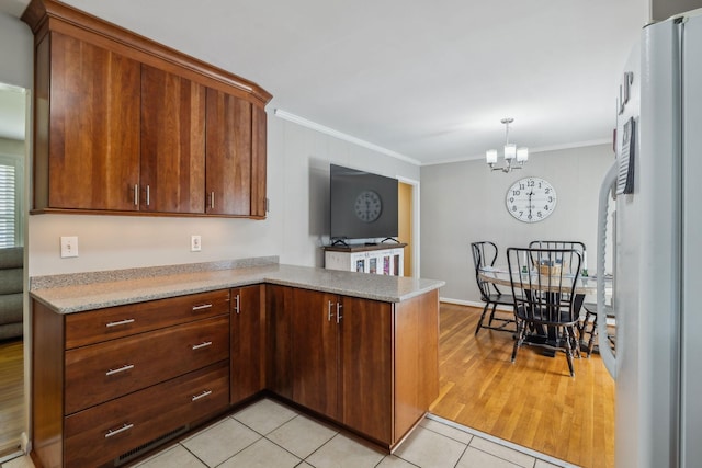 3132 Stafford Dr, Nashville, TN 37214 - kitchen with freestanding refrigerator, light tile patterned floors, ornamental molding, and a notable chandelier
