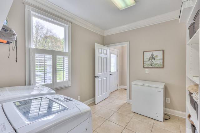 clothes washing area featuring laundry area, ornamental molding, light tile patterned floors, washing machine and dryer, and baseboards