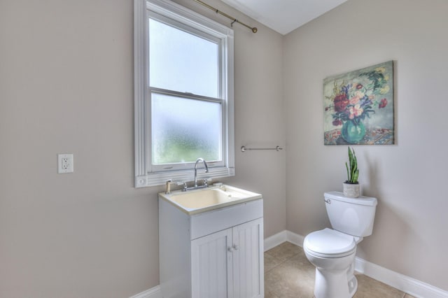 half bathroom with tile patterned floors, baseboards, vanity, and toilet