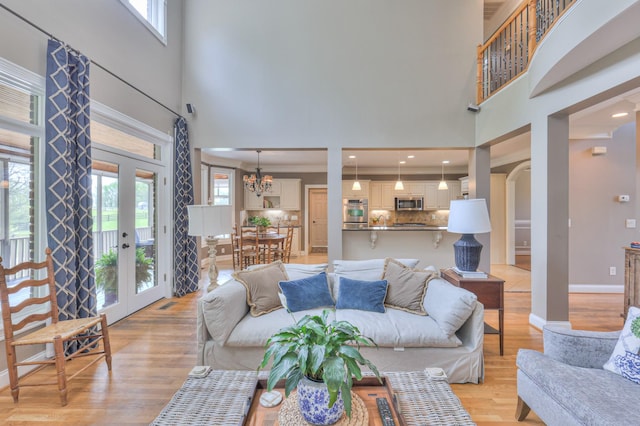 living room with baseboards, a healthy amount of sunlight, a towering ceiling, and light wood-style flooring