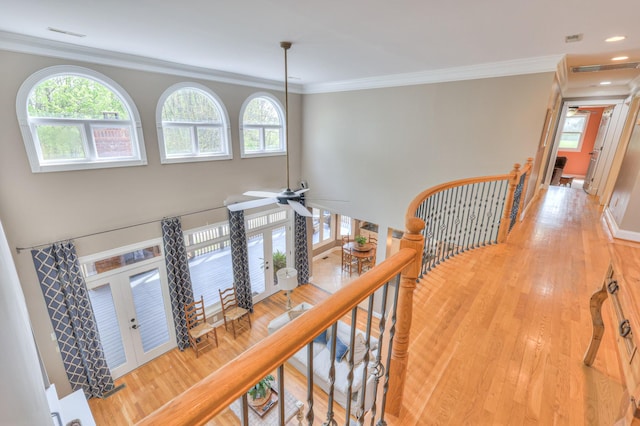 hall with ornamental molding, french doors, an upstairs landing, and light wood-style floors