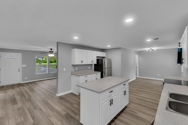 kitchen with light wood-type flooring, open floor plan, a center island, freestanding refrigerator, and a sink
