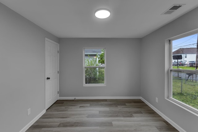 empty room featuring visible vents, baseboards, and wood finished floors