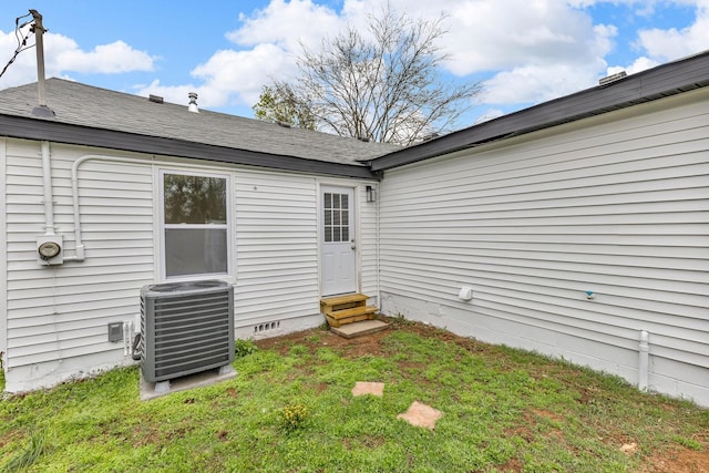 rear view of property featuring crawl space, central air condition unit, a lawn, entry steps, and a shingled roof