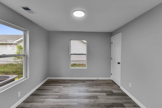 empty room featuring wood finished floors, baseboards, and visible vents