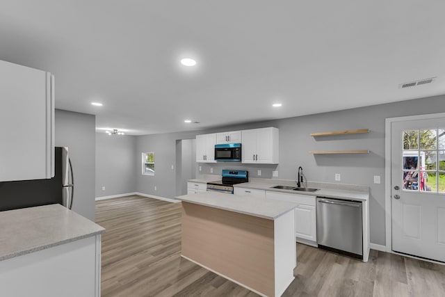 kitchen with light wood-type flooring, white cabinetry, visible vents, stainless steel appliances, and a sink
