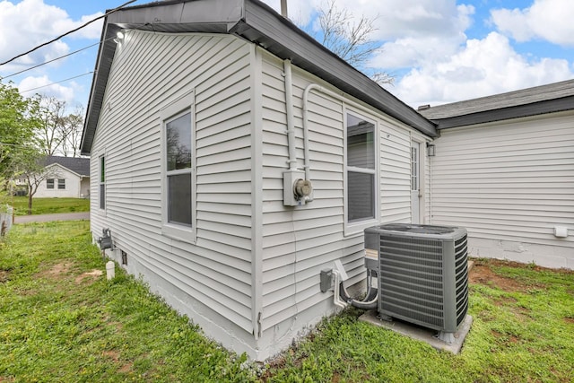 view of side of property with a yard and central AC