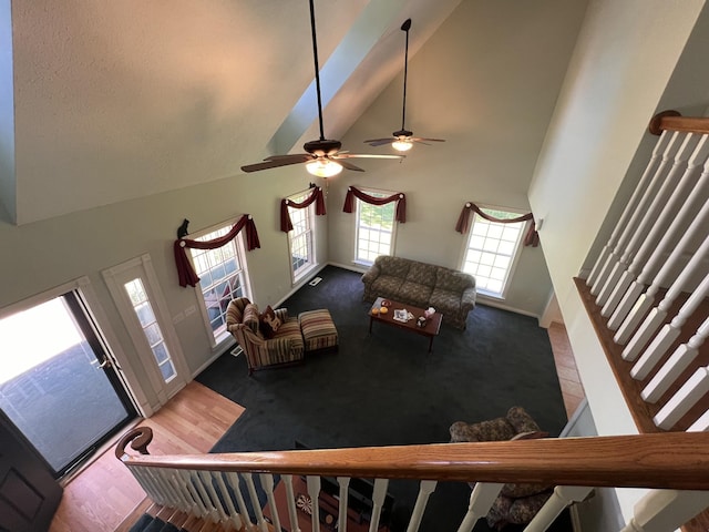 living room featuring high vaulted ceiling, carpet floors, stairway, a ceiling fan, and baseboards