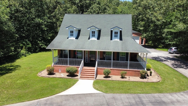 cape cod-style house with a front lawn, roof with shingles, covered porch, and aphalt driveway