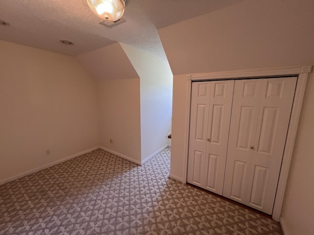 bonus room featuring baseboards, lofted ceiling, visible vents, and a textured ceiling