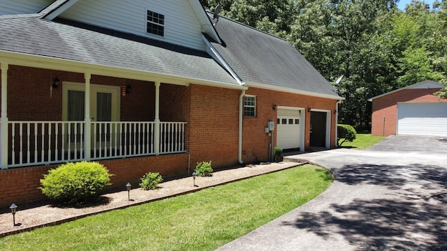 view of property exterior featuring roof with shingles, french doors, driveway, brick siding, and a garage