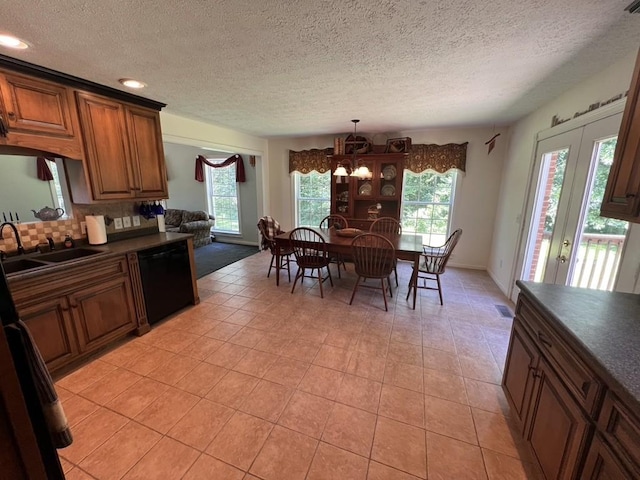 kitchen with a sink, backsplash, dishwasher, brown cabinetry, and dark countertops