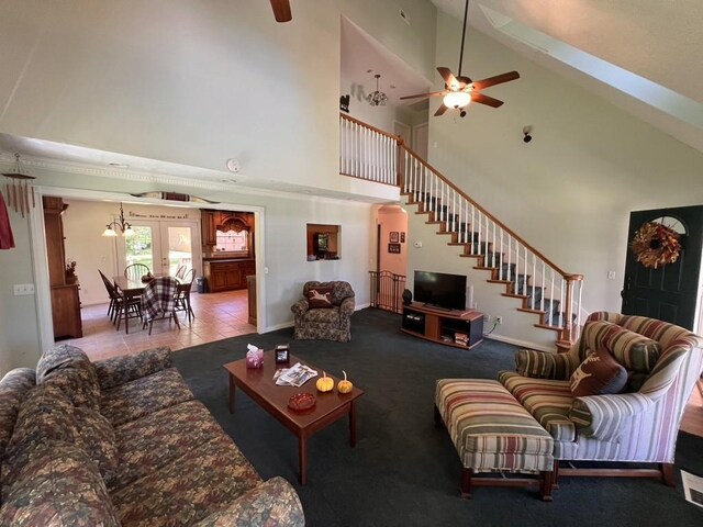 tiled living room featuring stairs, french doors, carpet, a towering ceiling, and a ceiling fan
