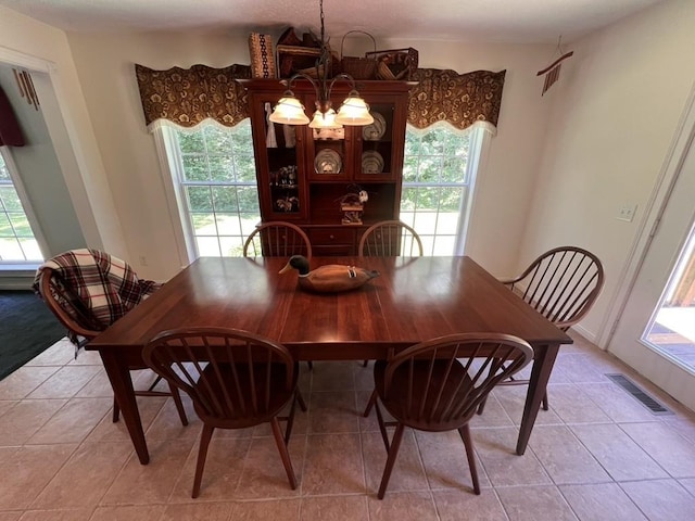 dining space featuring light tile patterned flooring, a notable chandelier, a healthy amount of sunlight, and visible vents