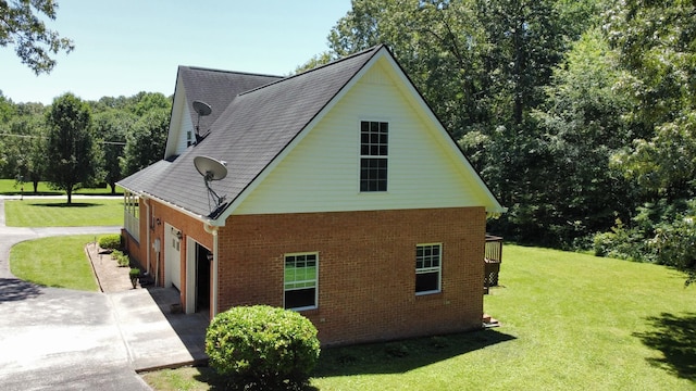 view of home's exterior featuring driveway, brick siding, a garage, and a yard