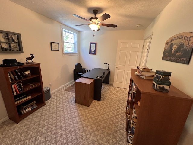 carpeted office featuring baseboards, ceiling fan, and a textured ceiling
