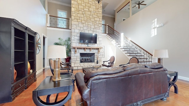 living area with crown molding, stairway, baseboards, a high ceiling, and a fireplace