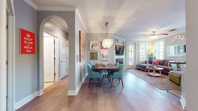 dining area featuring arched walkways, crown molding, baseboards, and wood finished floors